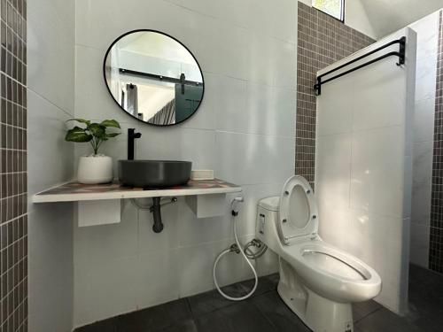 a bathroom with a toilet and a mirror at บ้านไร่ดอกแก้ว in Chom Bung