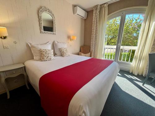 a bedroom with a large bed and a large window at Hôtel des Vignes - Juliénas in Juliénas