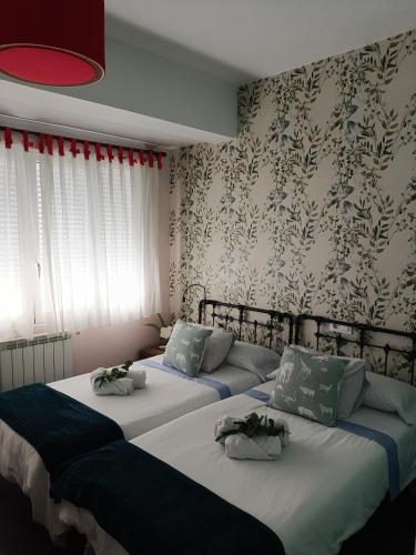 two beds in a bedroom with floral wallpaper at Luminoso Loft in Monforte de Lemos