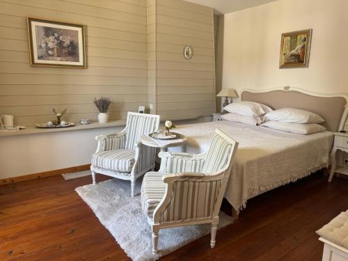 a bedroom with a bed and two chairs and a table at Le Patio Des Senteurs in Verzeille