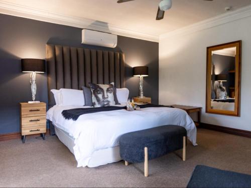 a bedroom with a large white bed and a mirror at The Woodpecker Inn in Pretoria