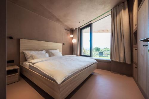 a bedroom with a large bed and a large window at Hotel Weingut Stroblhof in Appiano sulla Strada del Vino