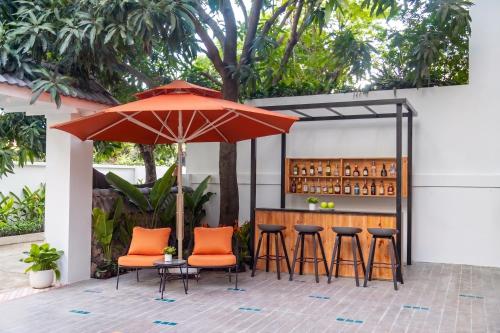 an outdoor bar with orange chairs and an umbrella at Dorm Beachside Hotel & Hostel By Haviland in Danang