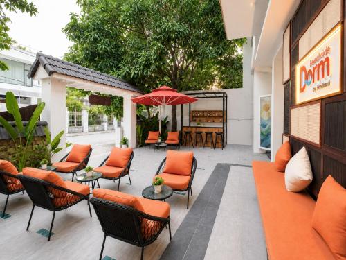 an outdoor patio with orange chairs and an umbrella at Dorm Beachside Hotel & Hostel By Haviland in Danang
