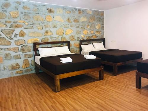 two beds in a room with a stone wall at Rock Retreat in Kanakapura