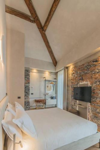 a bedroom with a white bed and a brick wall at La Corte del Lario - La Cortesella in Varenna