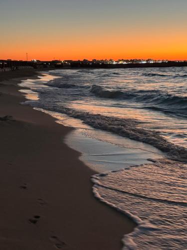 a beach at sunset with footprints in the sand at Al Obayed Garden Villa in Marsa Matruh