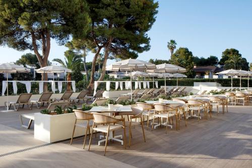 a row of tables and chairs with umbrellas at Alua Linda Mallorca - Newly Renovated 2026 in Can Pastilla