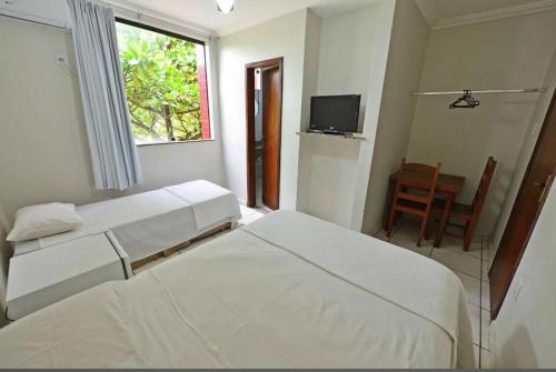 a bedroom with two beds and a tv and a window at Hotel Castanheira in Ipatinga