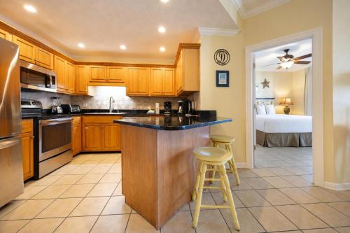 a kitchen with wooden cabinets and a counter with two stools at Phoenix VI 61408 in Orange Beach
