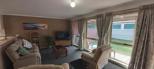 a living room with two couches and a tv and windows at Margarets Lane in Warrnambool