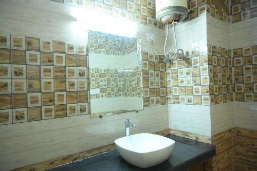 a bathroom with a white sink and a mirror at Mansarover Hotel & Banquets in Bareilly