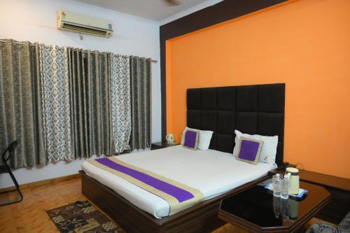 a bedroom with a large bed with an orange wall at Mansarover Hotel & Banquets in Bareilly