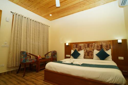a bedroom with a bed and a table and a chair at Vasant Corbett Resort By Mannat in Rāmnagar