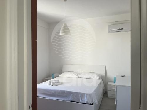 a bedroom with a white bed and a pendant light at La Torre - Piano Primo By Cala Salento in Torre Lapillo