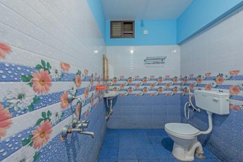 a bathroom with a toilet and flowers on the wall at Prince Park in Pondicherry