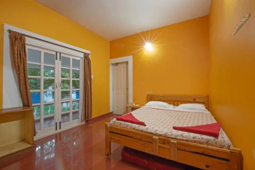 a yellow bedroom with a bed and a window at Prince Park in Pondicherry