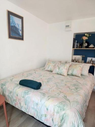 a bed with a blue pillow on it in a room at Le Nid, petit studio cosy et central in Besançon