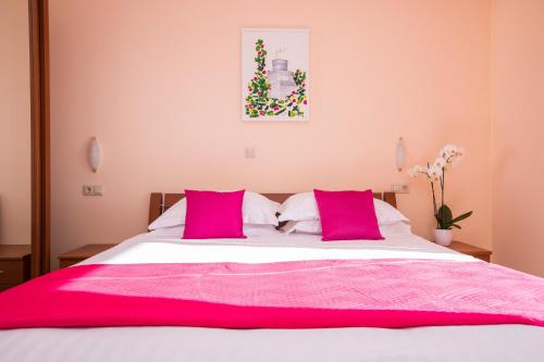 a bedroom with a large bed with pink pillows at Apartments Grbic in Mlini