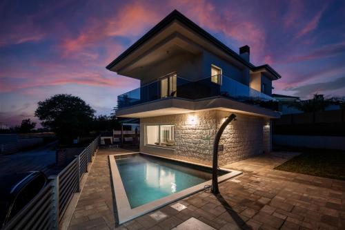 a house with a swimming pool in front of it at Villa Tadini JOY in Babići