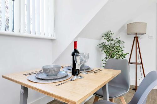 a dining room table with a bottle of wine on it at Addenbrookes Apartment in Trumpington