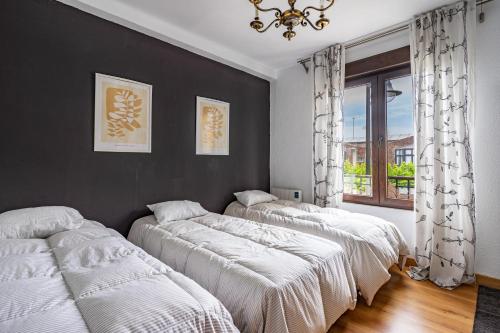 three beds in a room with a window at Little Yellow House in Gijón