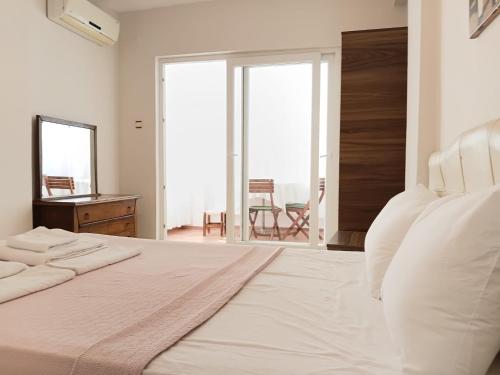 a white bedroom with a large bed and a dresser at Nese Otel in Çeşme