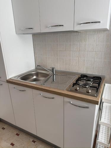 a white kitchen with a sink and a stove at La casa di GiòGiò in San Vito lo Capo