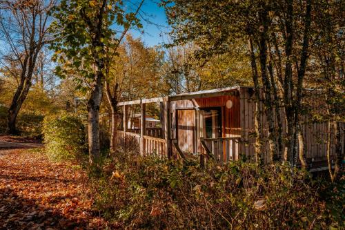 a small house in the woods with trees at Village Vacances de Combelles in Le Monastère