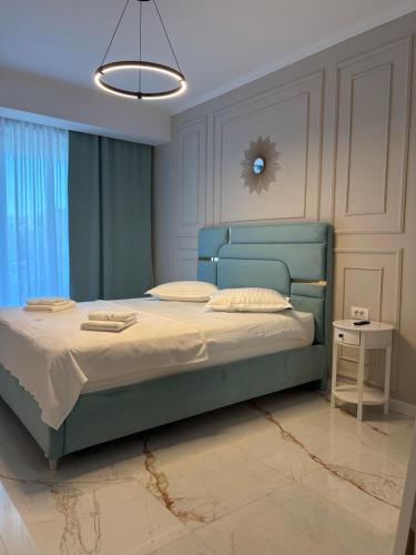 a bedroom with a bed with a blue head board at F&Lrelax-Apartamente de închiriat aproape de plajă in Mamaia Sat/Năvodari