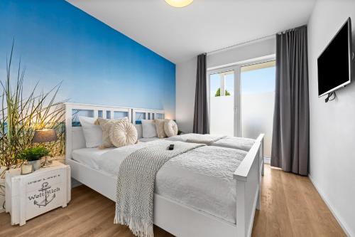 a bedroom with a white bed and a blue wall at Ferienwohnung WeitBlick Olpenitz in Olpenitz