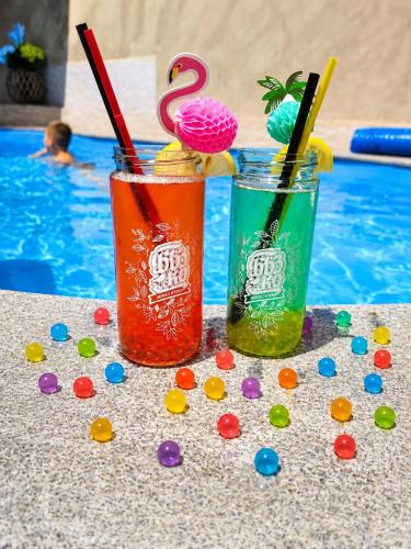 two colorful drinks sitting next to a swimming pool at Хотел PERLA in Strelcha