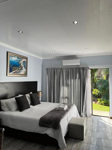 a bedroom with a large bed and a large window at Gemstone Guest House in Klerksdorp
