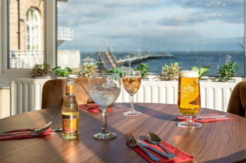a wooden table with two glasses of beer on it at The Grand Hotel in Llandudno