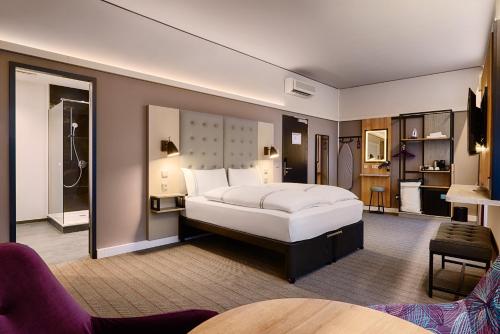 a bedroom with a large white bed and a bathroom at Premier Inn Koeln City Centre in Cologne
