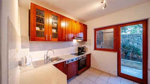 a kitchen with wooden cabinets and a sink and a window at Waterfront Villa Dora by Villas Guide in Smokvica