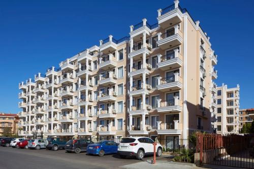 a large white building with cars parked in front of it at Polarstar Beach Resort - Premium Apartments in Sveti Vlas