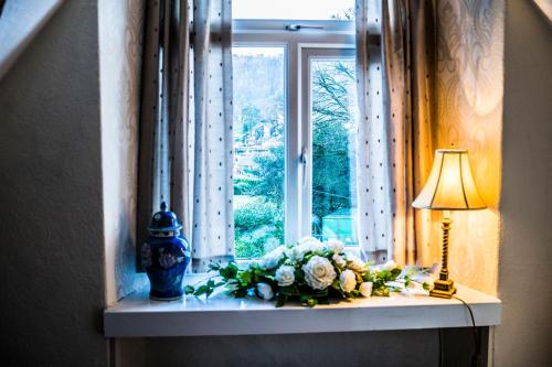 a vase filled with flowers next to a window at Lake View Guesthouse in Bowness-on-Windermere