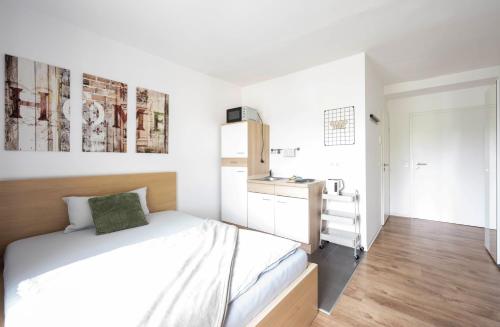 a white bedroom with a bed and a kitchen at N4 - Apartments Fulda Free Parking & Zentral in Fulda