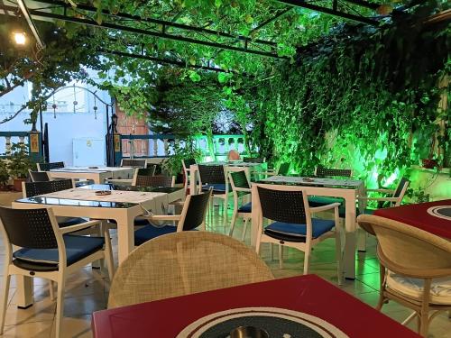 a restaurant with tables and chairs and vines at Nese Otel in Çeşme