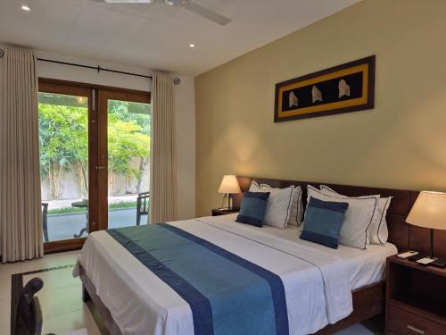a bedroom with a large bed and a balcony at Coastal Villa Mirissa in Mirissa