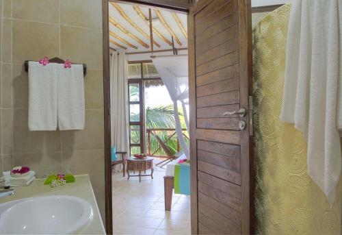 a bathroom with a tub and a sink and a door at Sultan Sands Island Resort & Spa in Kiwengwa