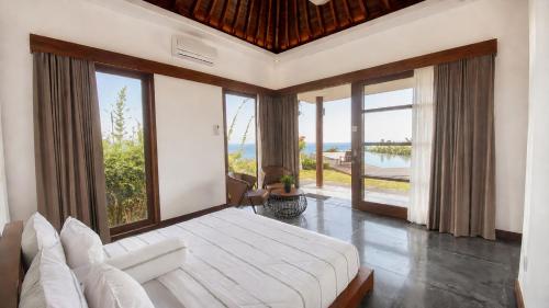 a bedroom with a large bed and large windows at Villa Layar with Private Pool and Ocean View in Lajor