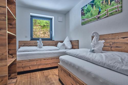two beds in a room with wooden walls and a window at Annies Bergwelt Haus Waldherz in Bodenmais