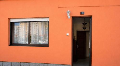 an orange wall with a window and a door at Casa Praia Norte - PVZ in Póvoa de Varzim