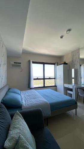 a bedroom with a bed and a couch and a window at Jtower Residences Rad Staycation in SM Jmall in Mandaue City