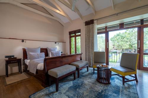 a bedroom with a bed and a chair and windows at Casterbridge Hollow Boutique Hotel in White River