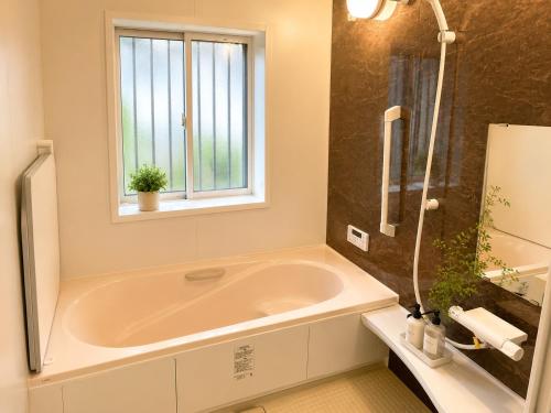 a bathroom with a large tub and a window at すずめのとまりぎ in Nasu