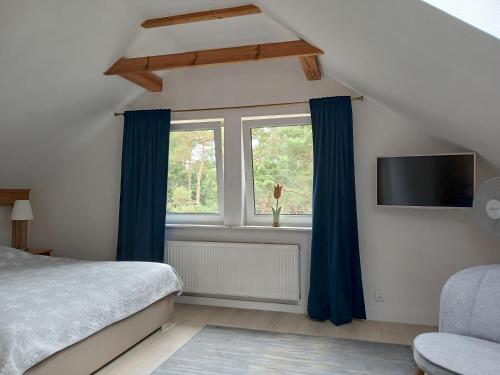 a bedroom with a bed with blue curtains and a tv at Przy Lesie Apartamenty Pokoje Parking in Pobierowo