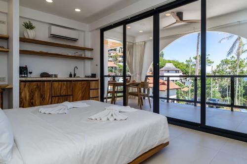 a bedroom with a white bed and a balcony at Aqueduct resort in Ko Tao